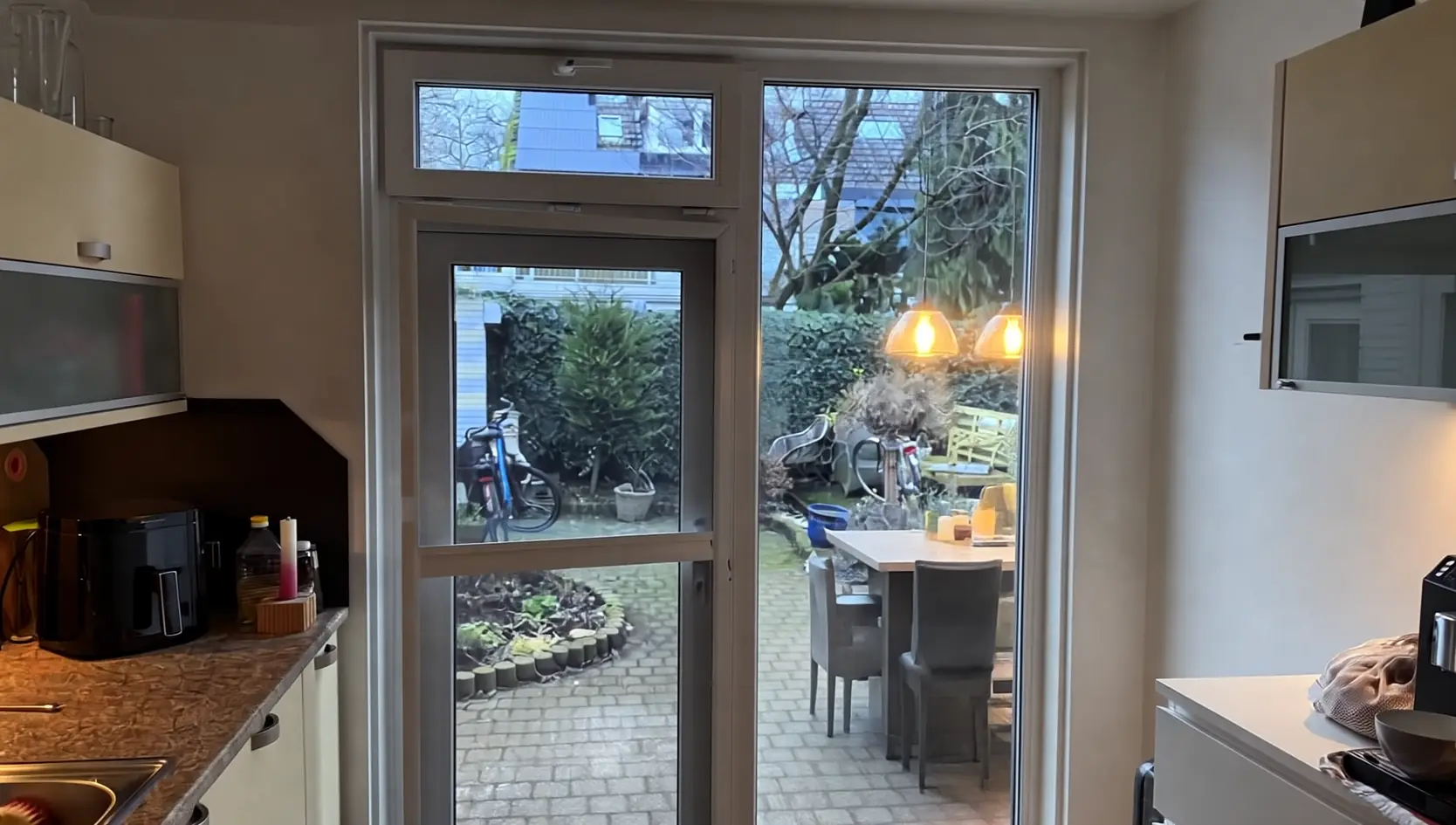 Witte tuindeur met bovenlicht en zijraam, gezien vanuit een keuken