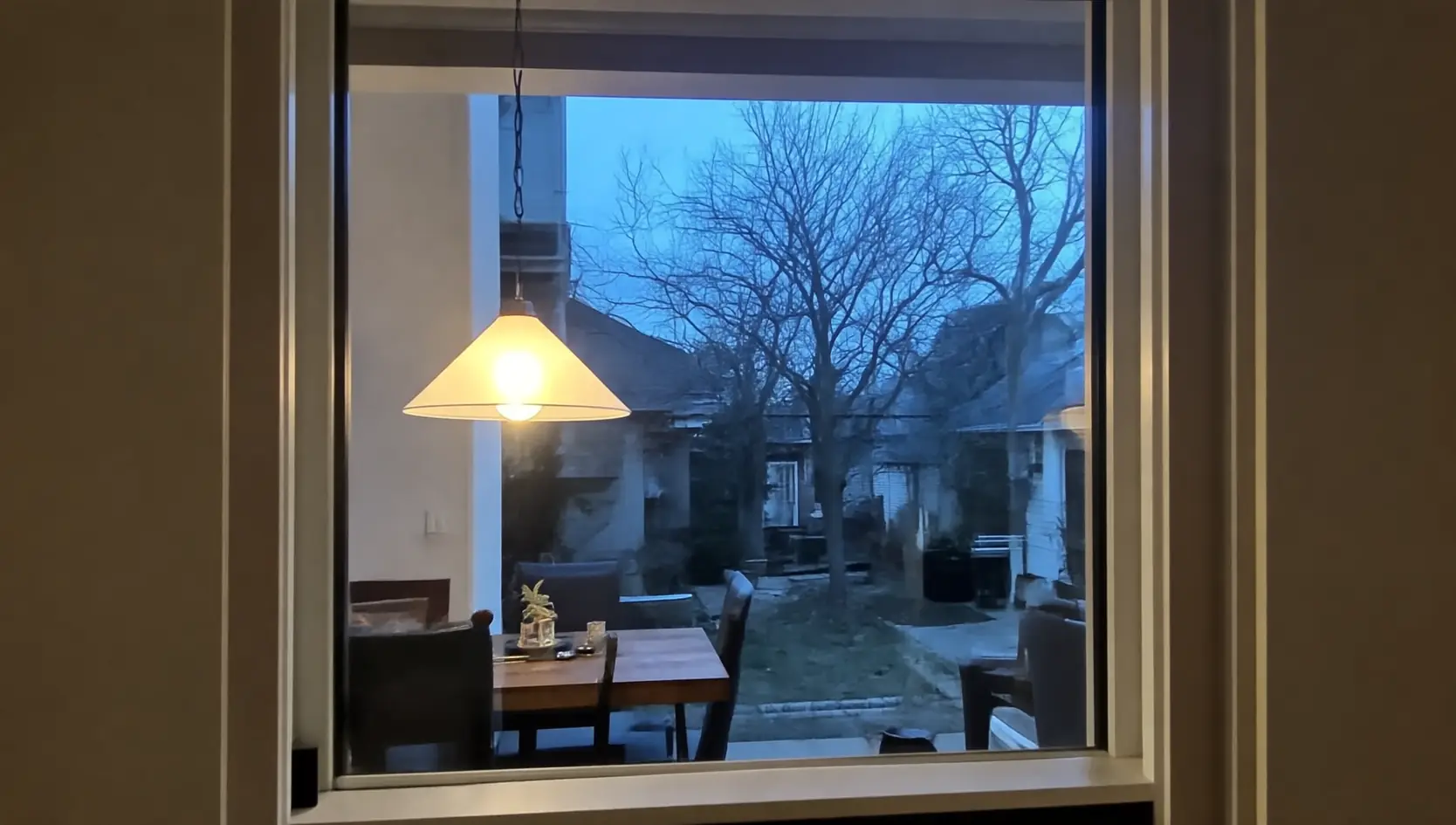 Wit raam in een woonkamer, met zicht op een tuin bij schemer
